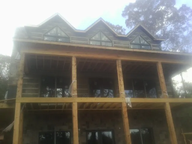 Dormers and porch framing on a large log home under construction — Roof Coating work by our crew in Estell Manor