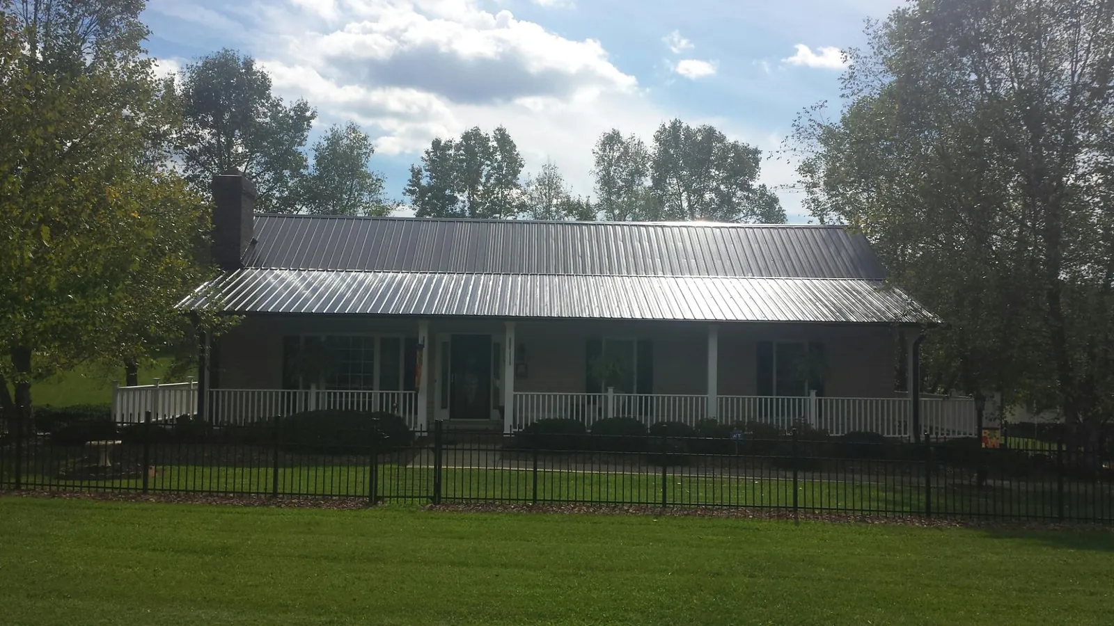 Gray metal roof on a brick ranch with a full width front porch — Gutter Guard Installation work by our crew in Estell Manor