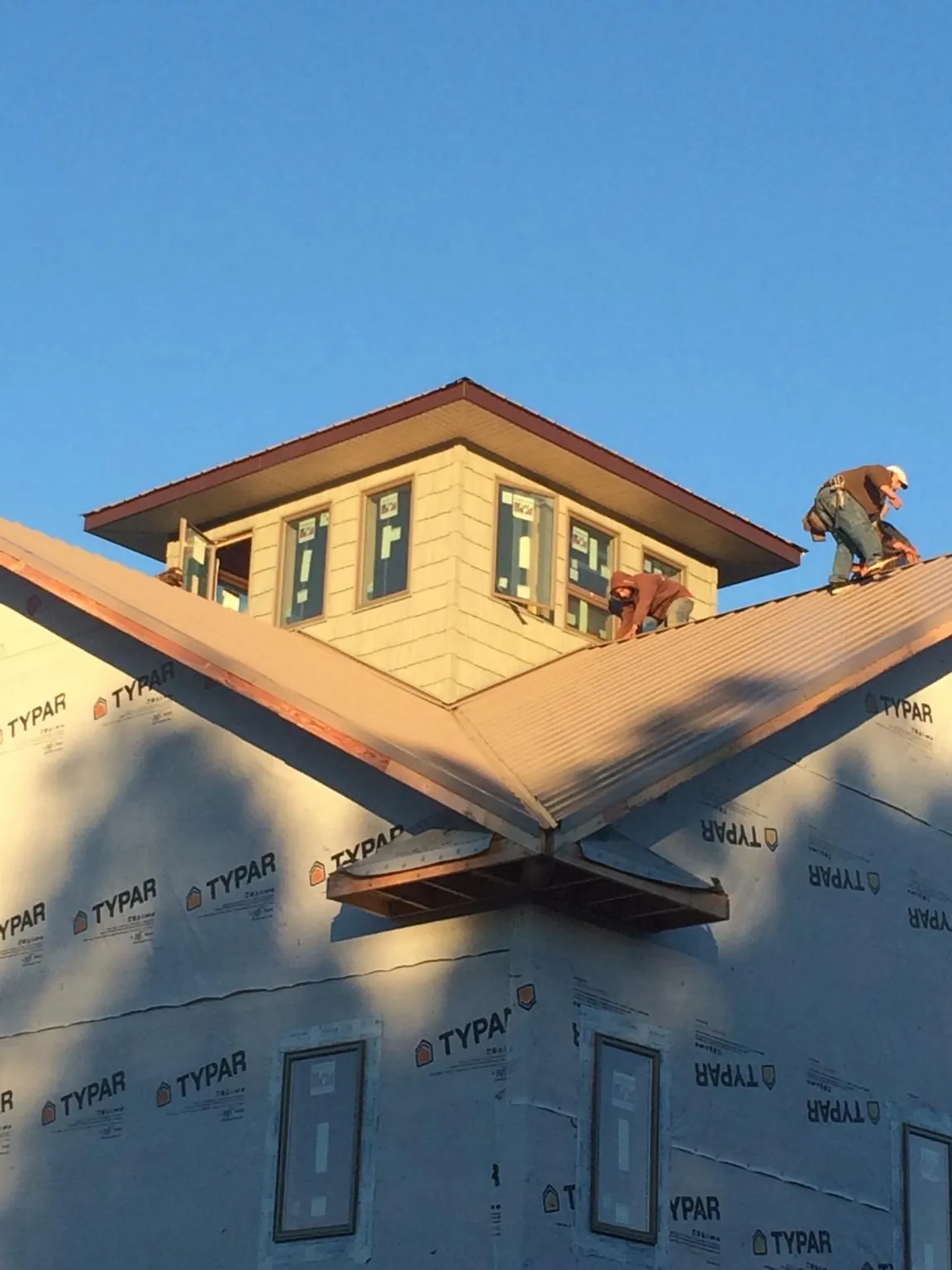 Roofers working around a rooftop cupola on a new metal roof at sunset — Roof Waterproofing in Estell Manor by Roofing Brothers
